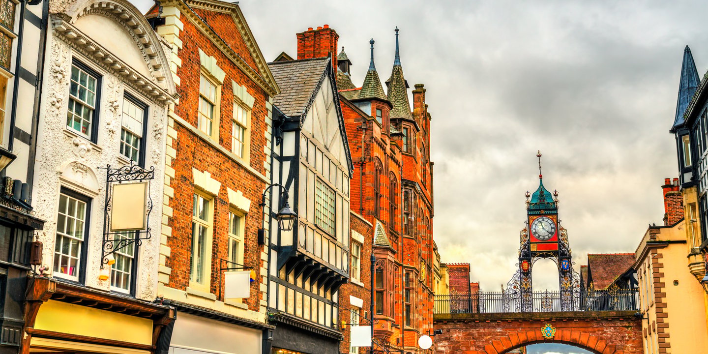 Historic Eastgate Clock and Tudor-style architecture in Chester, England, under a cloudy sky.