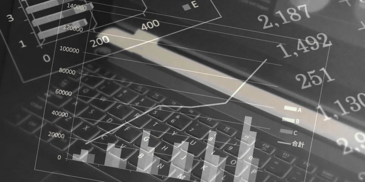 Dados financeiros digitais e gráficos de análise de negócios sobrepostos ao teclado de um laptop.