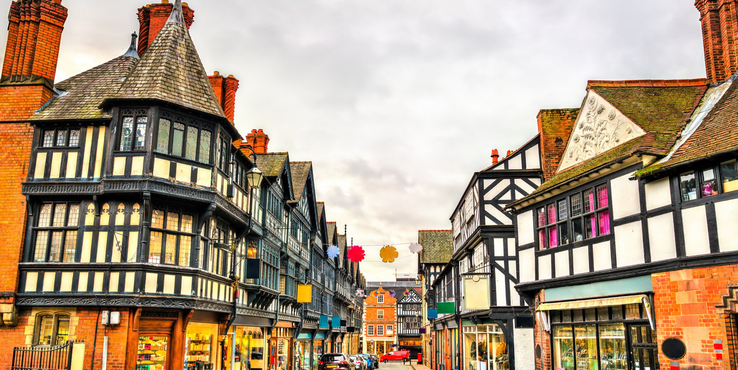 Traditional half-timbered Tudor style buildings and shops lining a historic street in Chester, England.