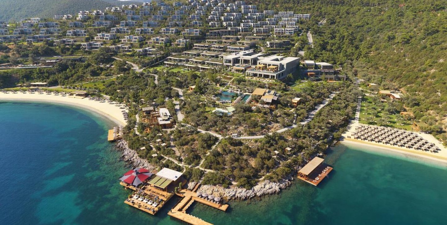 Aerial view of a luxury Aegean sea resort with modern villas, private beaches, and wooden docks in Bodrum.