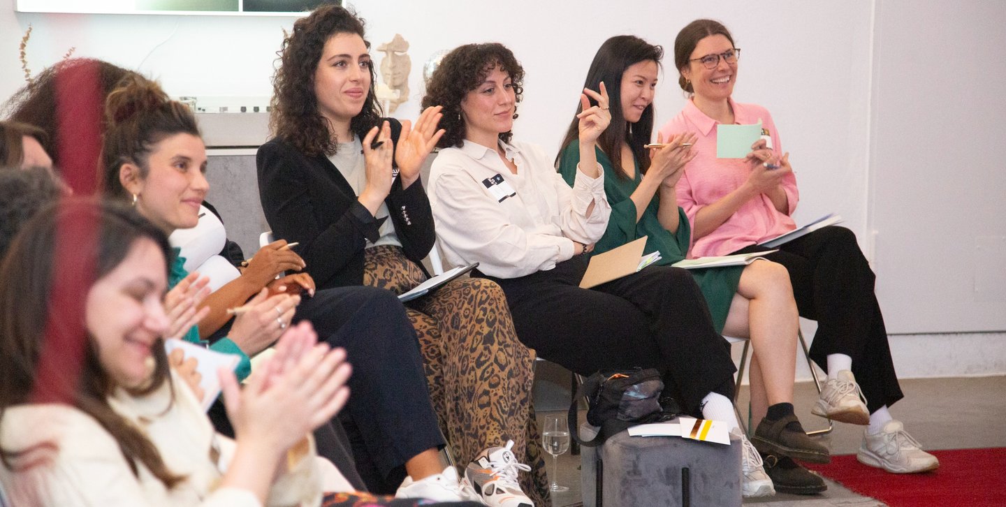 Women applauding for women at public speaking workshop