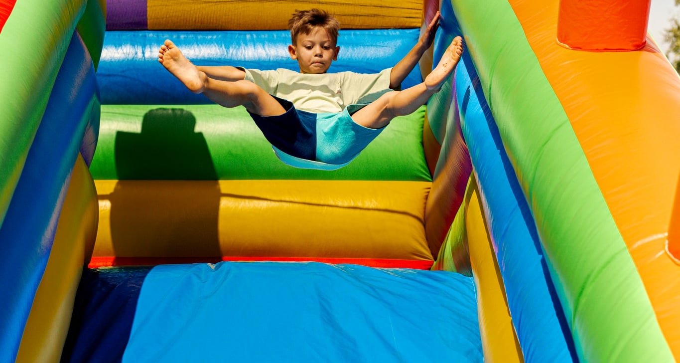 a boy is playing on a slider in a bouncer
