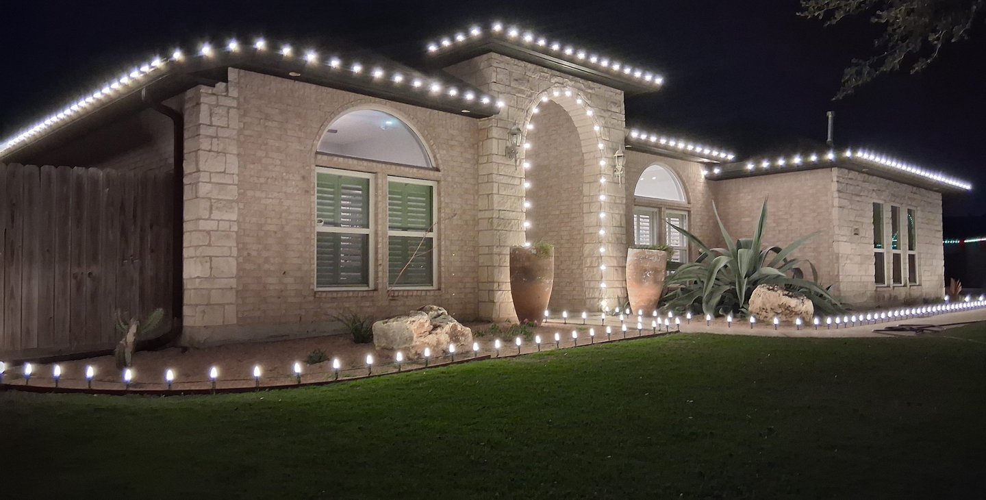 Corpus Christi house decorated with white LED Christmas roofline and walkway lights at night.