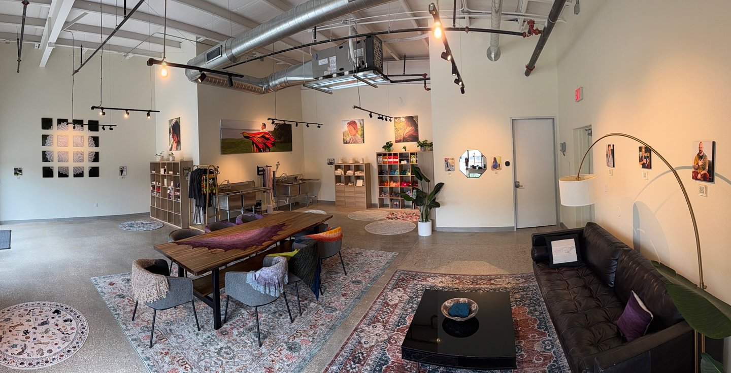 A panoramic image of a yarn shop with communal space to work.