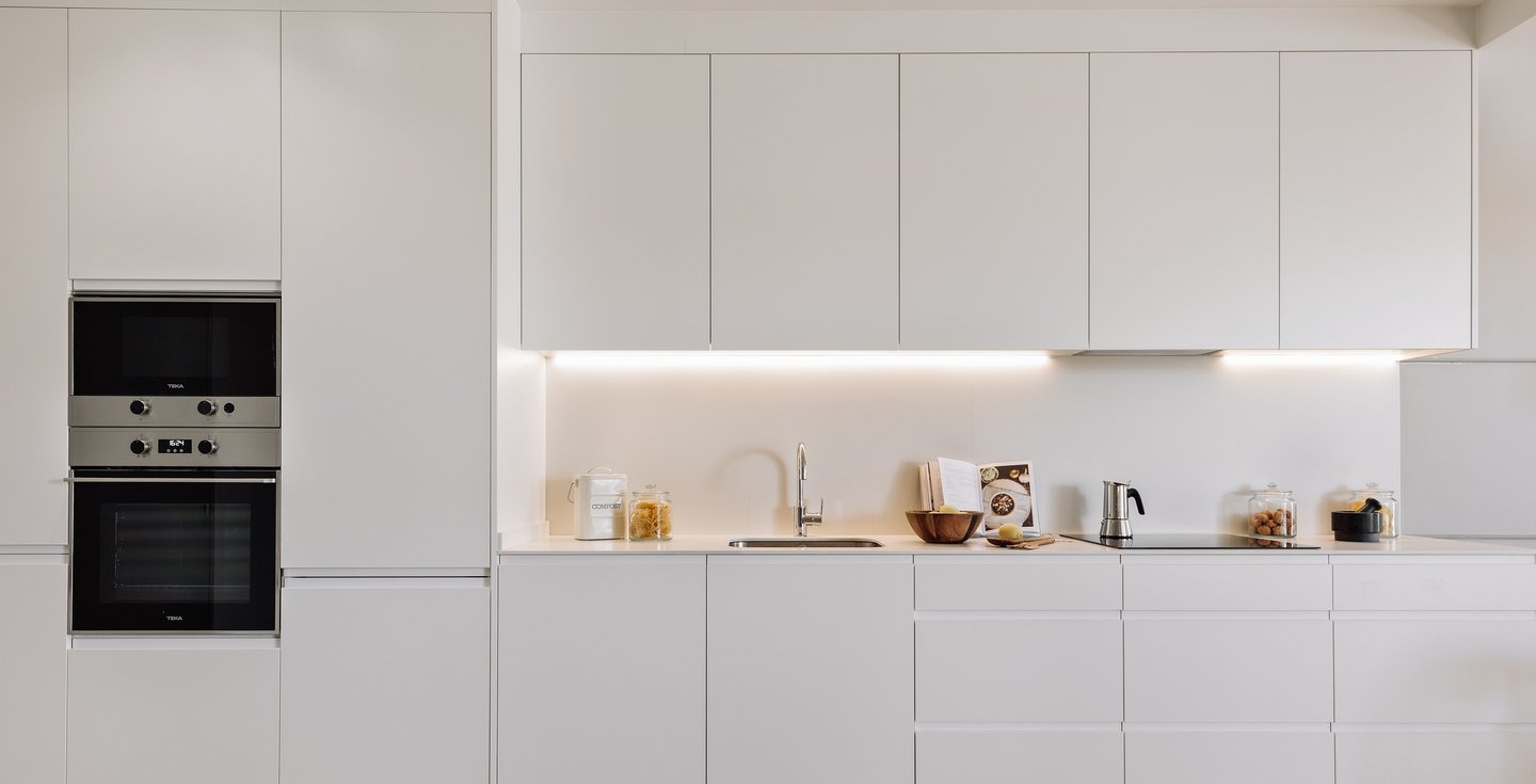 Open-plan kitchen with white cabinets and state-of -the-art appliances for contemporary apartment