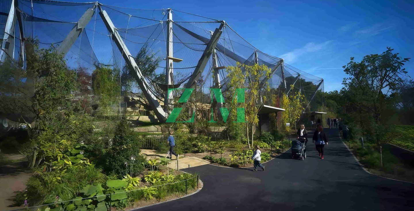 Visitors walk past the large mesh enclosure of the Land of the aviary exhibit