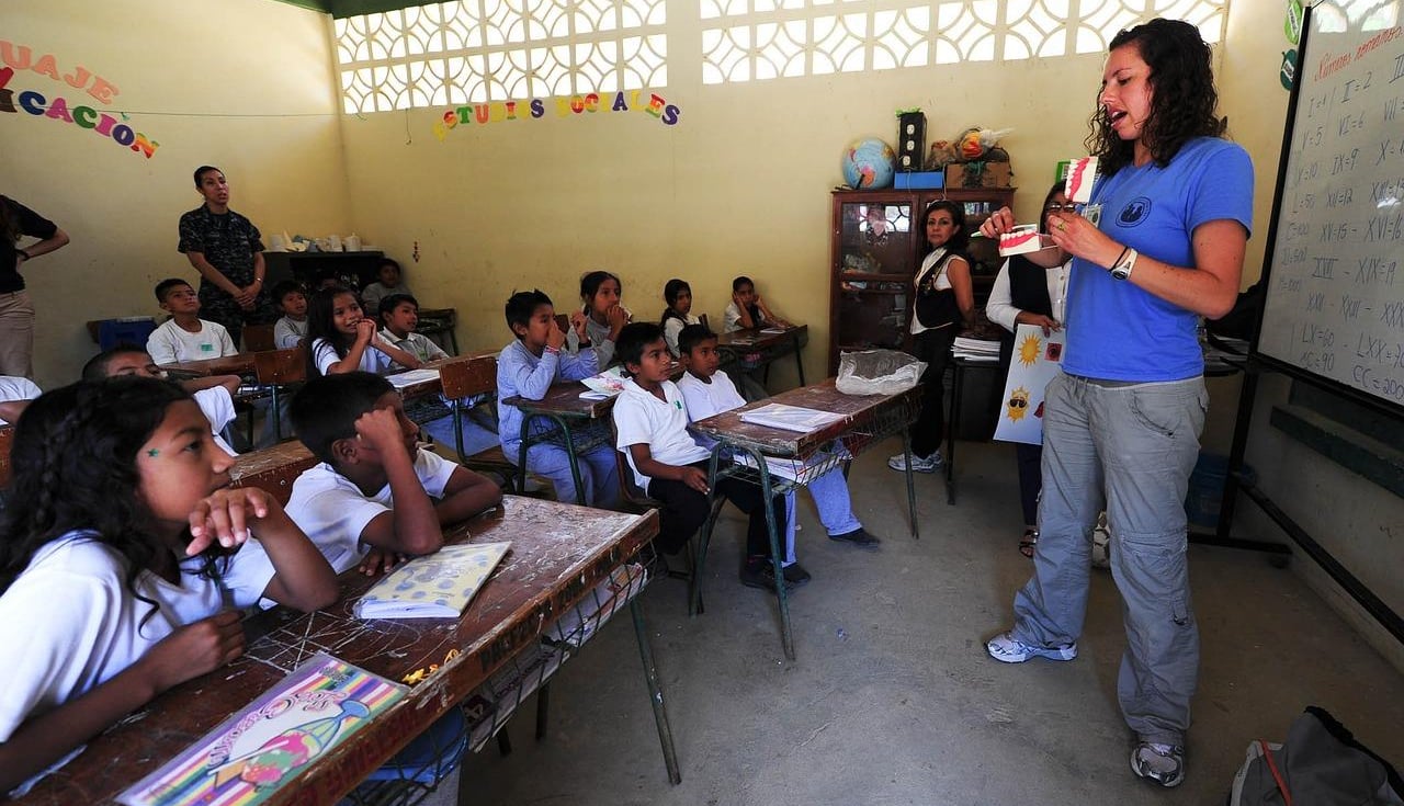 International classroom, students at desk, teacher in front of room