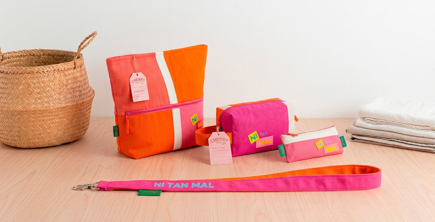 Handmade pink and orange canvas cosmetic bags and matching fabric leash on a wooden table.
