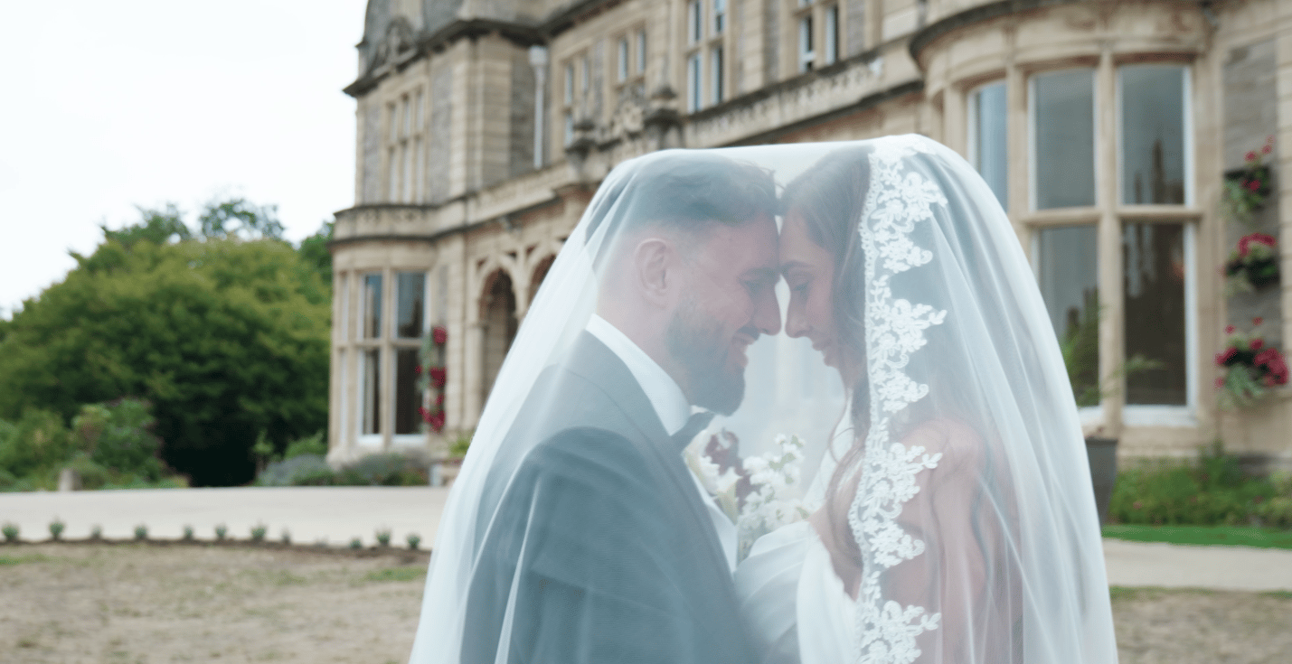 Bride and groom pose together in front of a large, elegant building, celebrating their wedding day.
