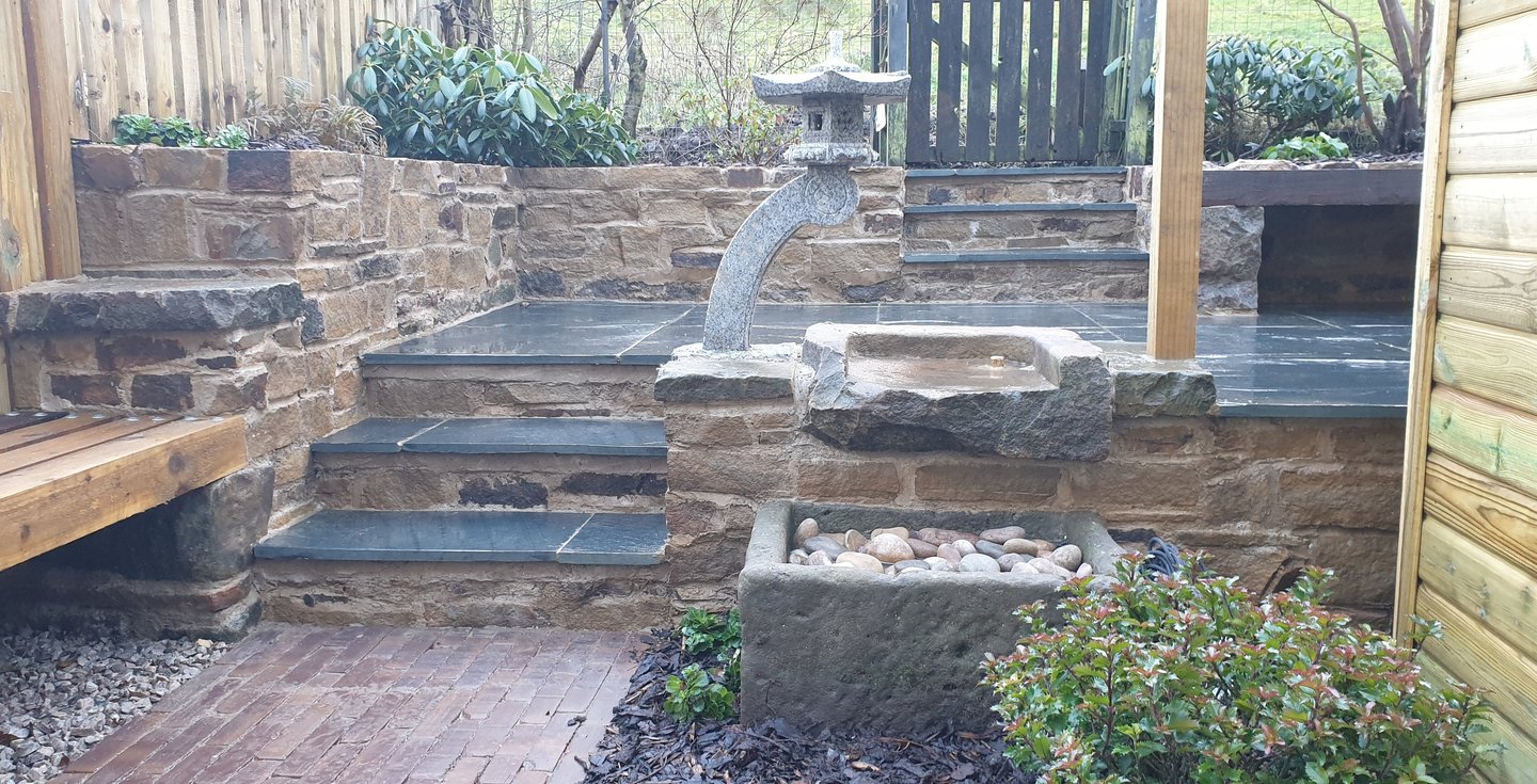 a stone fountain in the middle of a japanese style garden makeover in Yorkshire