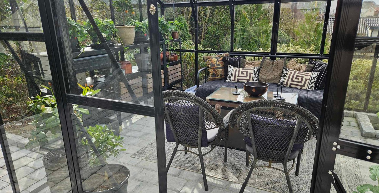 The interior of a greenhouse with comfy seats and storage by garden designer Magnus Steen