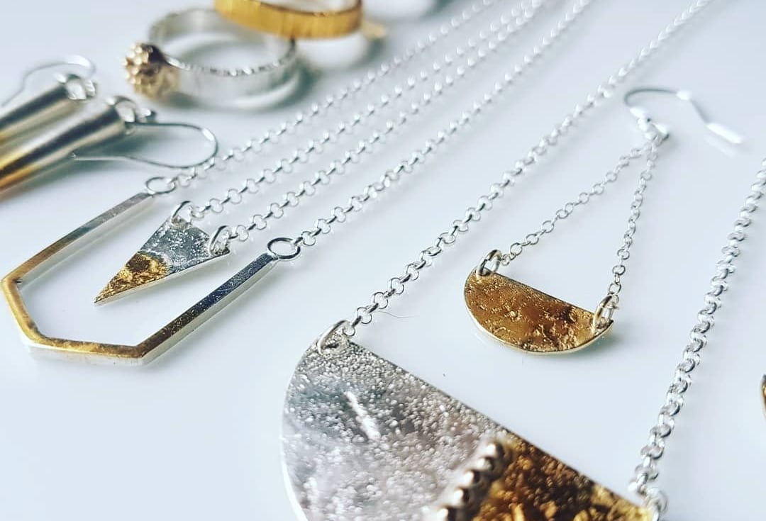 Handmade mixed metal jewellery including silver and gold geometric necklaces, rings, and earrings.