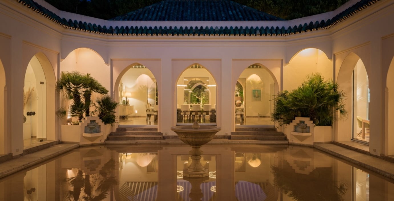 Courtyard at Villa El Rincon featuring a central fountain surrounded by flooded reflective flooring and classic arches.