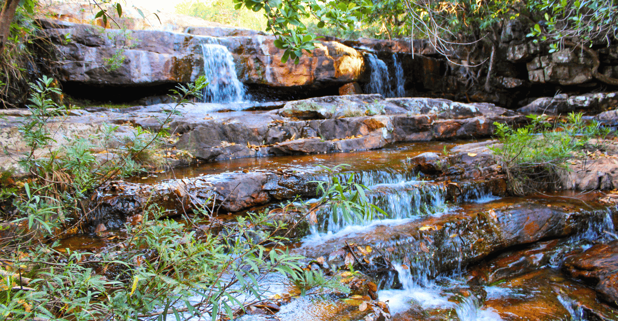 Pequenas quedas d'águas em paredes pequenas de pedras e vetação, em uma cachoeira em MG