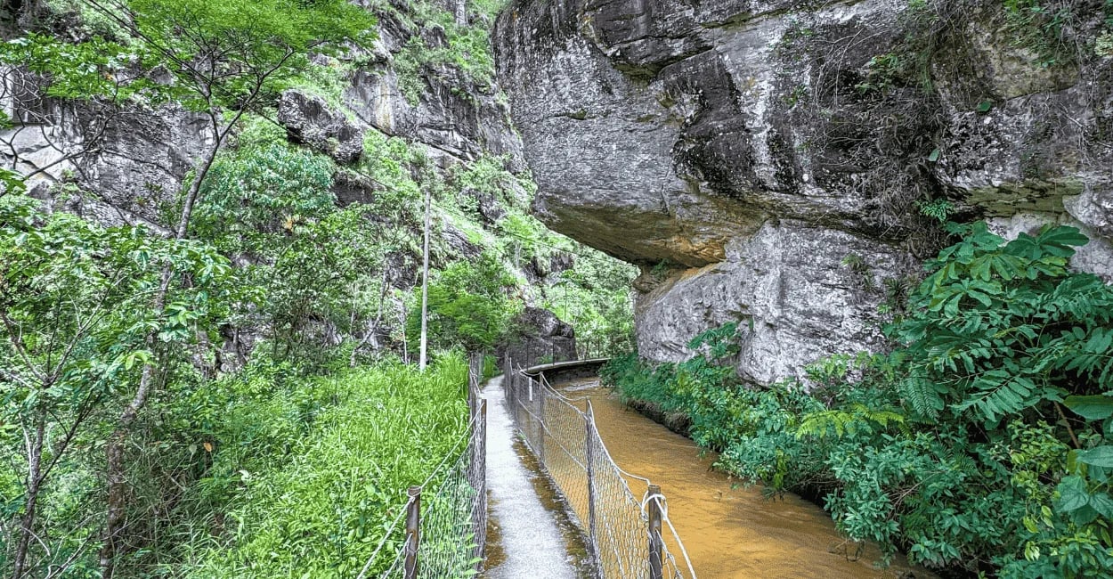 Passarela estreita passando sob uma imponente rocha suspensa no Cânion do Funil em Santo Antônio do 
