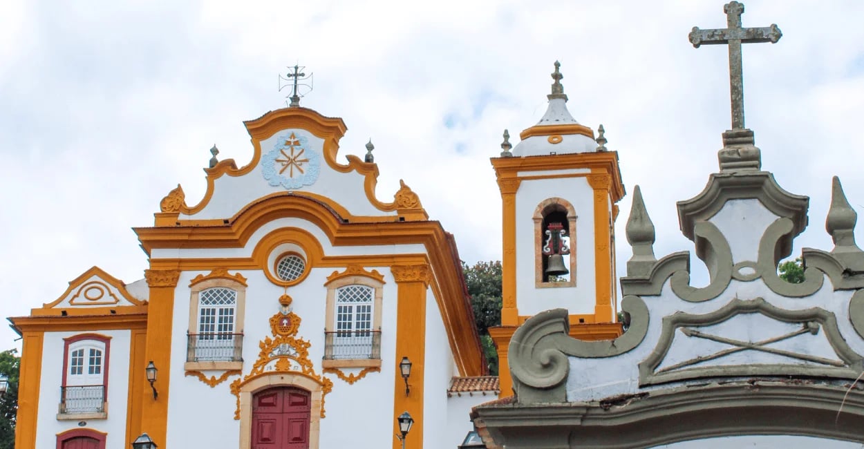 Igreja histórica em São João del-Rei com fachada branca e amarela, torre com sino e cruz