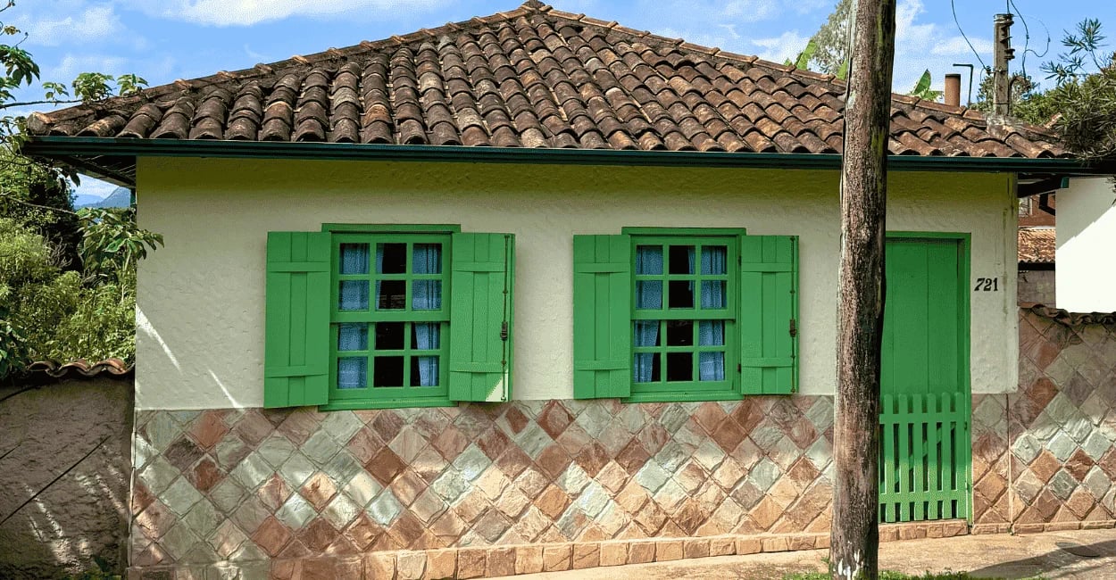 Casa colonial com janelas verdes e telhado de barro em Lavras Novas, distrito histórico de Ouro Pret