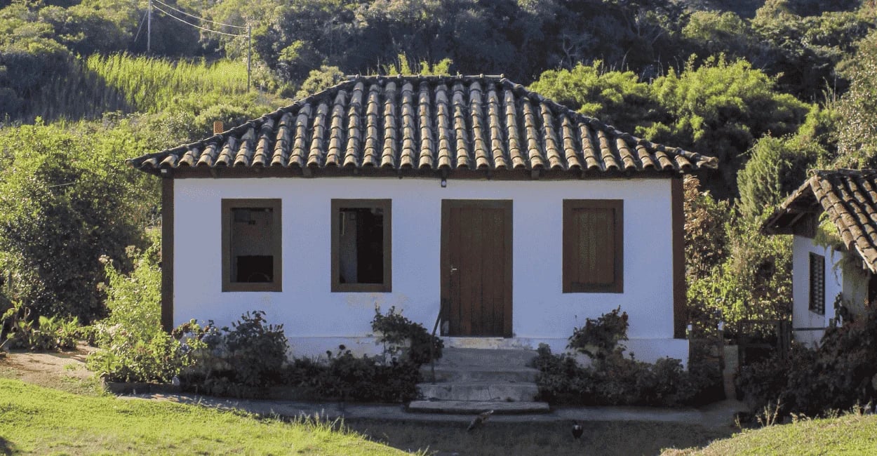 Casa histórica de arquitetura simples em Casa Grande, Minas Gerais, cercada por vegetação e área rur