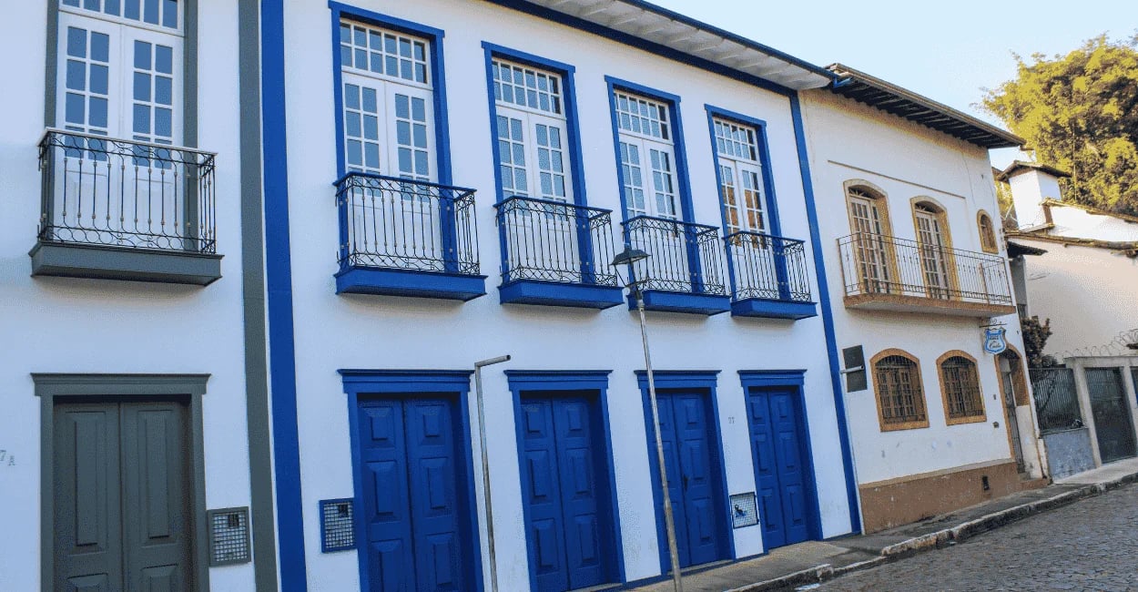 Casarões históricos com portas azuis, sacadas de ferro e rua de pedra em Sabará MG