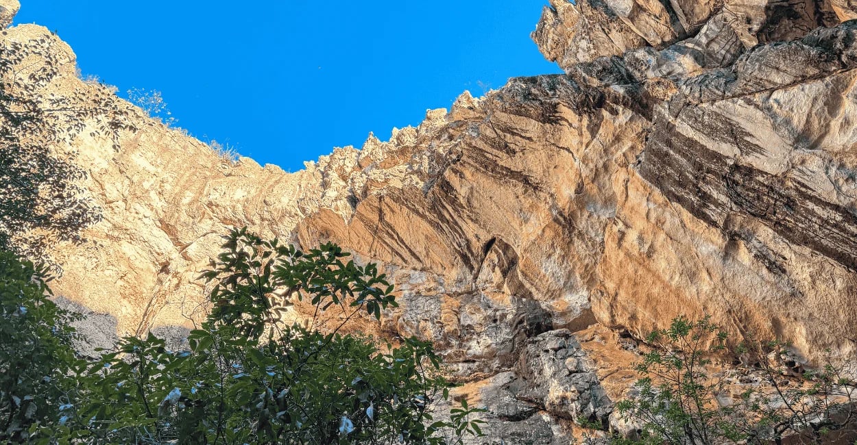 Formação rochosa com vegetação próxima e céu azul, na Gruta do Salitre em MG