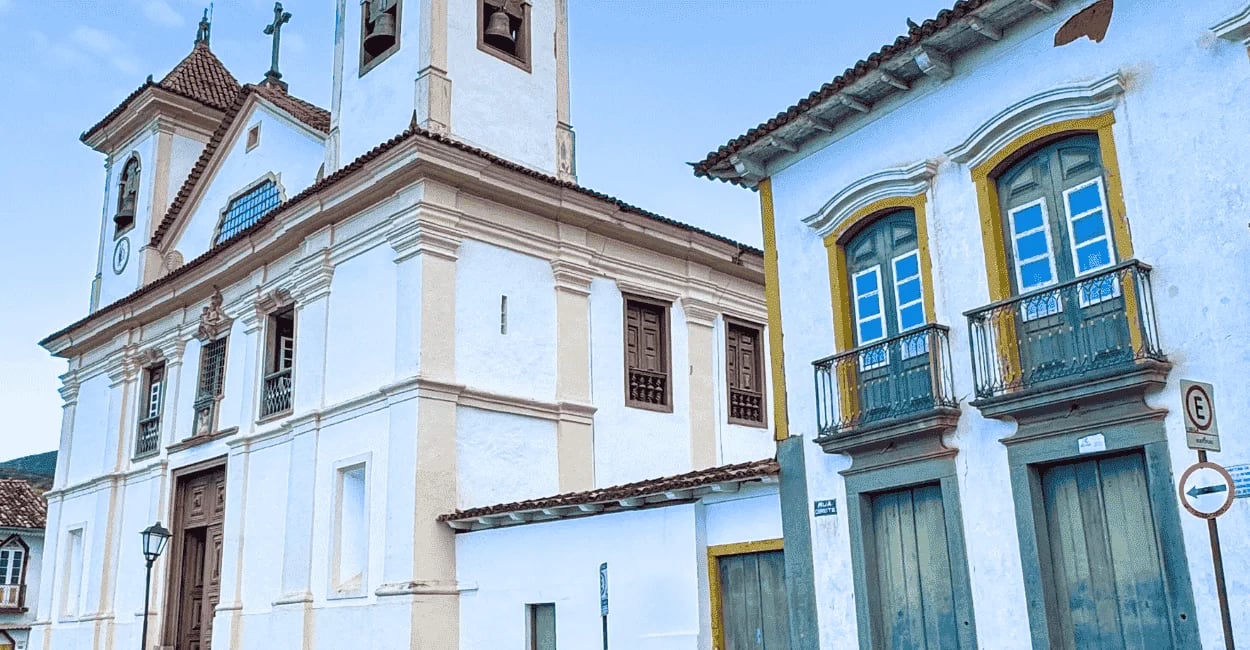 Igreja Matriz da Sé em Mariana com fachada histórica, casario colonial e janelas coloridas ao lado
