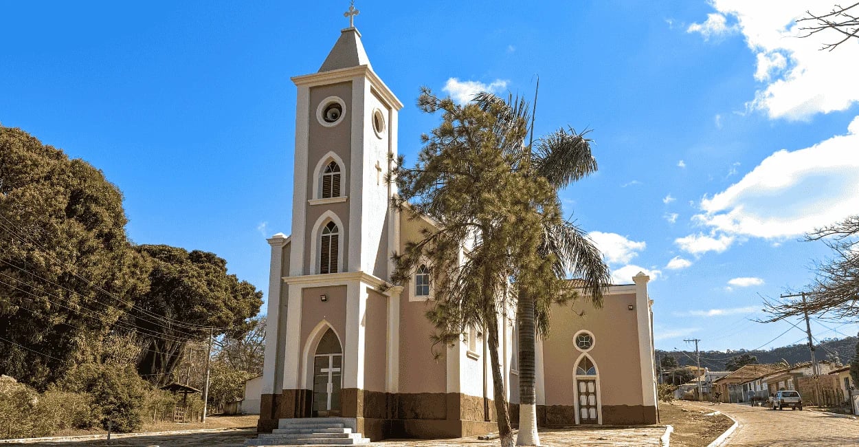 Igreja Matriz de Conselheiro Mata em Diamantina MG com torre alta, palmeiras e céu azul