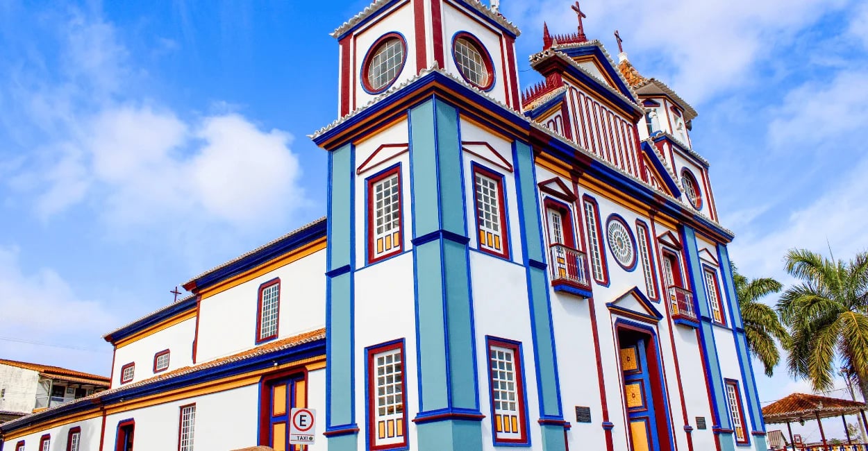 Igreja Matriz de Datas, em Minas Gerais, com fachada colorida e céu azul