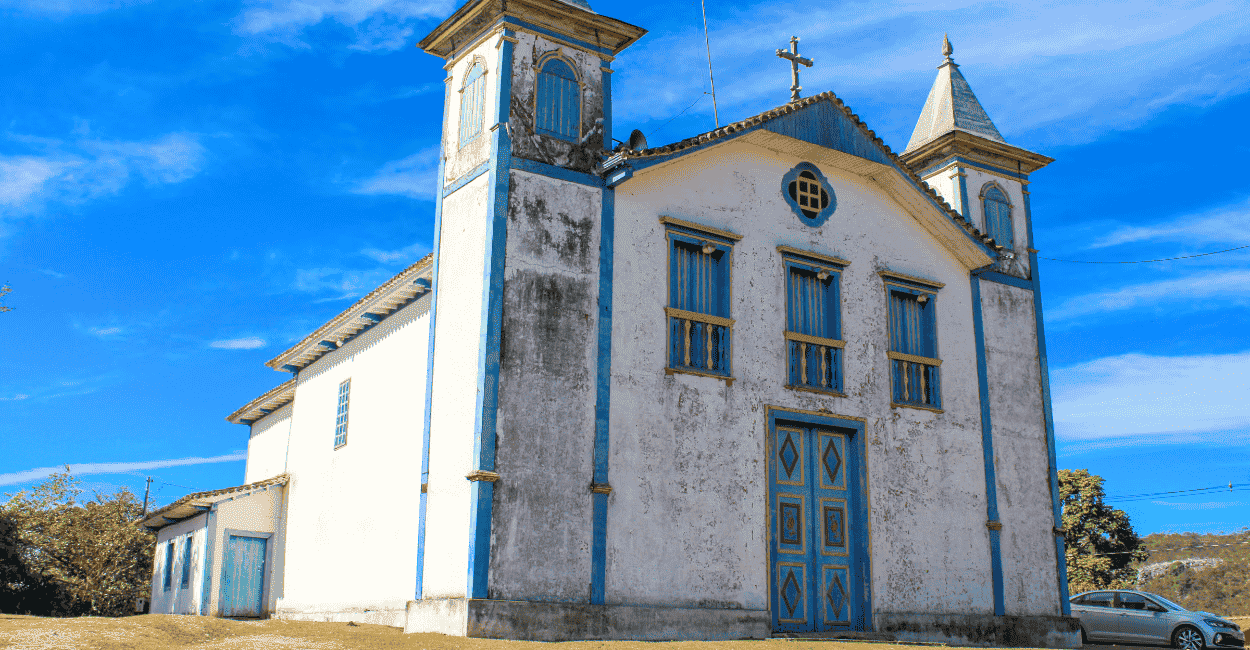 Igreja Matriz de São Gonçalo do Rio das Pedras, com cores brancas e azueis, com céu aberto