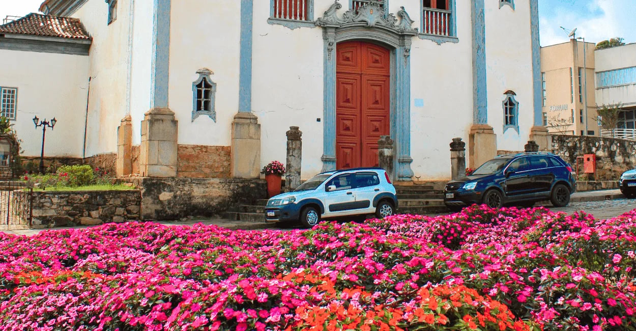 Igreja histórica em Santa Bárbara com porta vermelha, flores, fachada colonial azul, branca