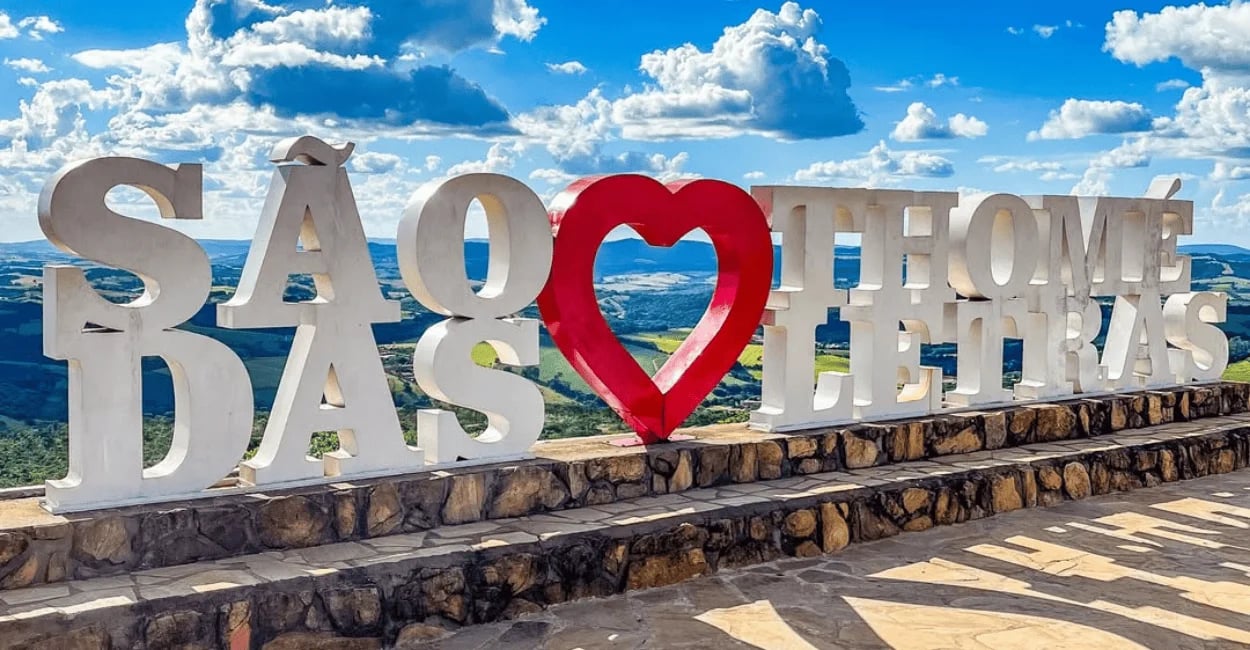 Letreiro de São Thomé das Letras com coração vermelho e vista panorâmica das montanhas mineiras