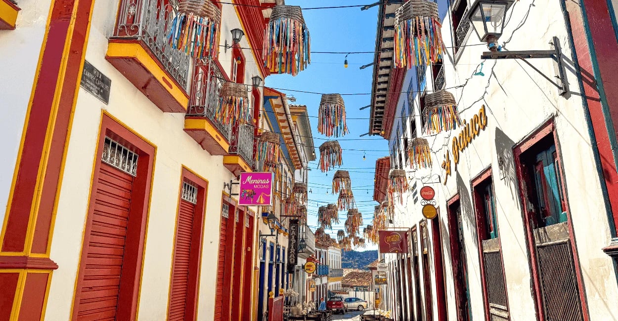 Rua histórica de Diamantina, com casario colorido, enfeites suspensos e céu azul