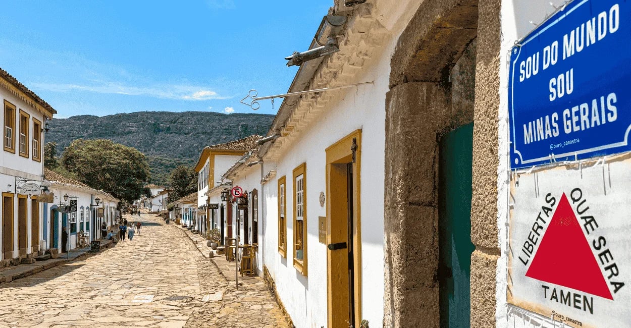 Rua de pedra com casario colonial, placa de Minas Gerais e serra ao fundo em Tiradentes