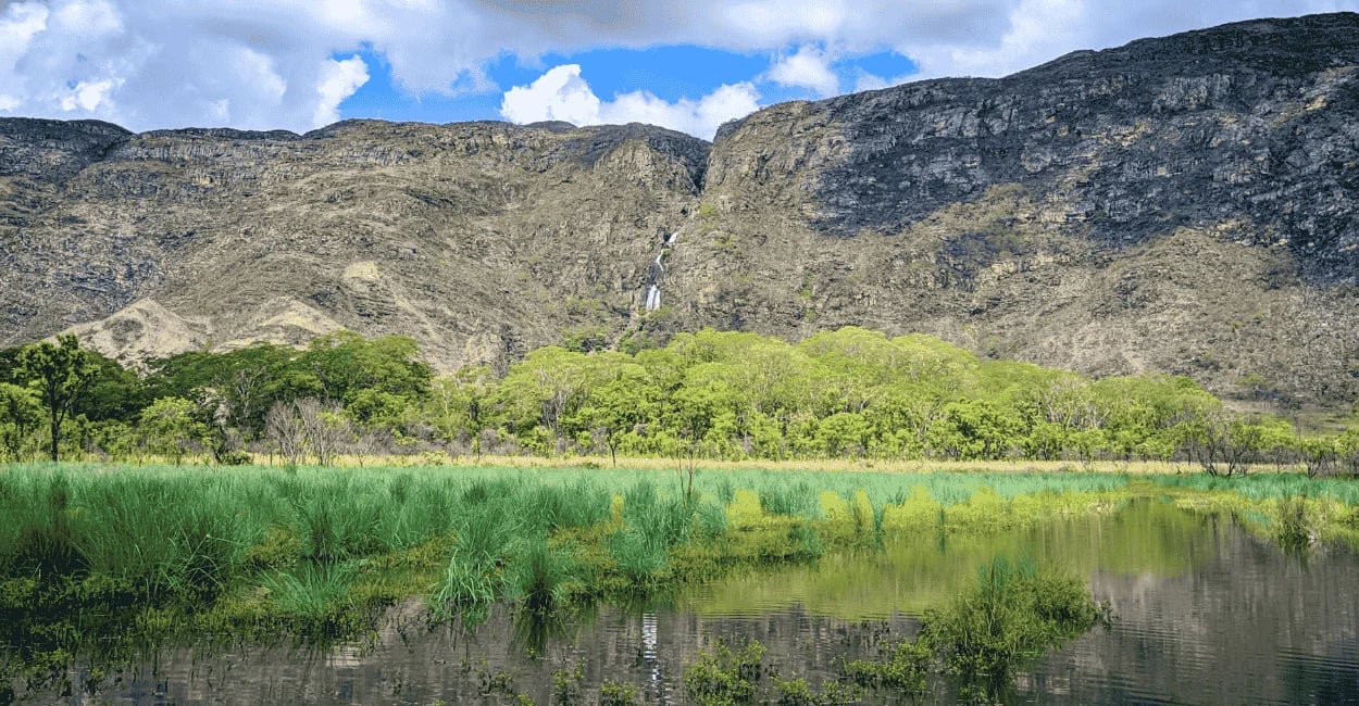 Espelho d'água e vegetação verde aos pés dos grandes paredões rochosos da Serra do Cipó, MG