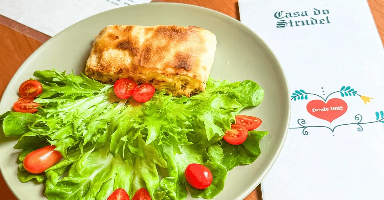 Prato da Casa do Strudel em Monte Verde, com strudel salgado, salada verde e tomates