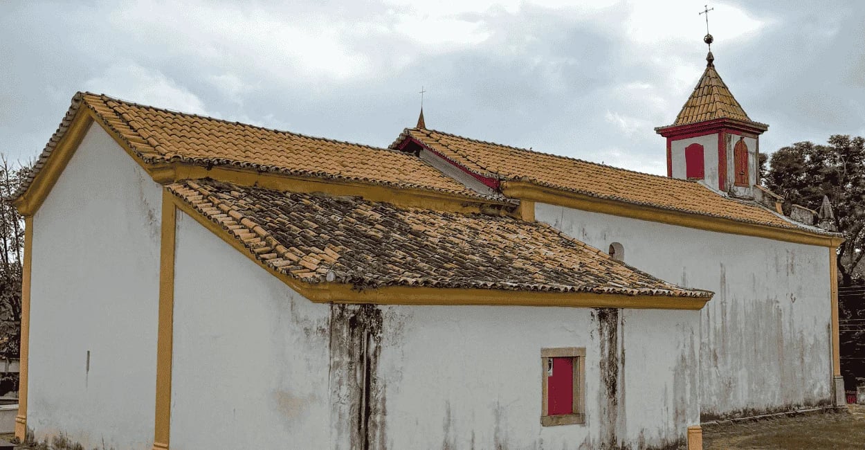 Vista lateral da Igreja de Santana em Cocais, com cores brancas e amarelas e uma torre
