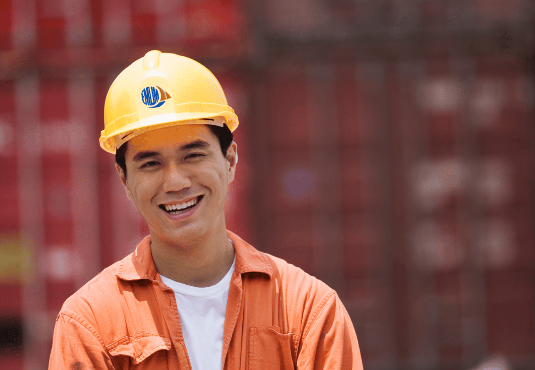 Man in Container Yard, wearing Warepack suit and helmet and smilling nice