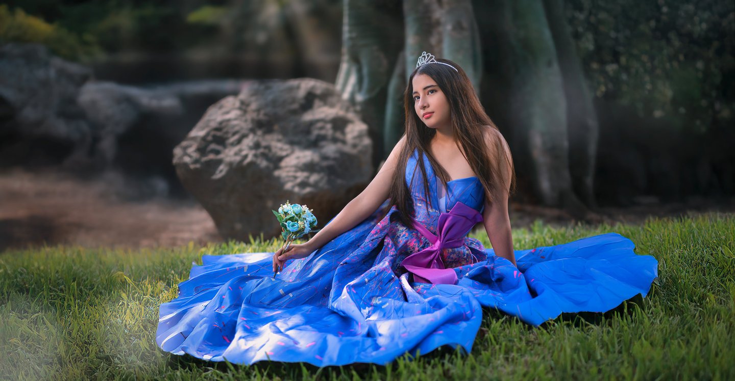 a woman in a blue dress sitting on the grass