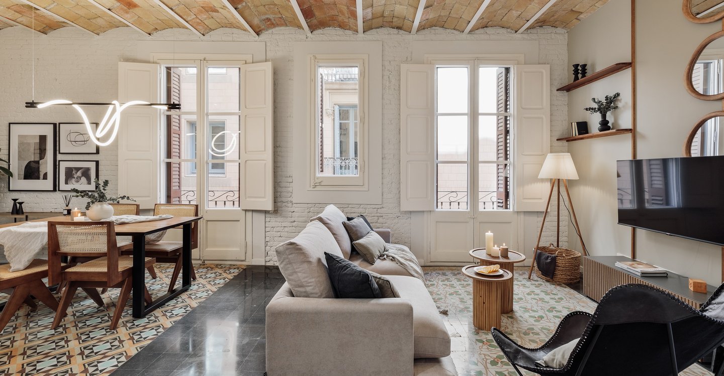 Modern living room featuring exposed brick walls, hydraulic tile floors, and Catalan vaulted ceiling