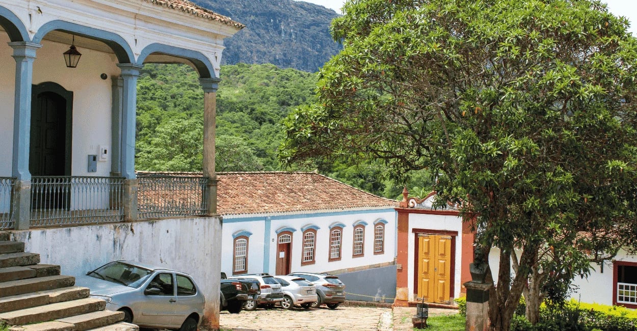 Casario colonial de Tiradentes com varandas históricas, igreja ao fundo e Serra de São José cercando