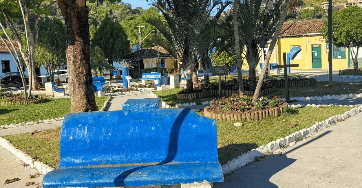 Praça de Ipoema com bancos azuis, jardins arborizados e clima tranquilo no interior de Minas Gerais