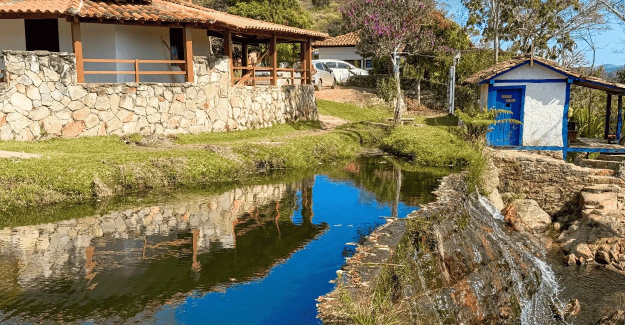 Queda d'água da Cachoeira do Comércio descendo por paredão de pedra em área de mata nativa