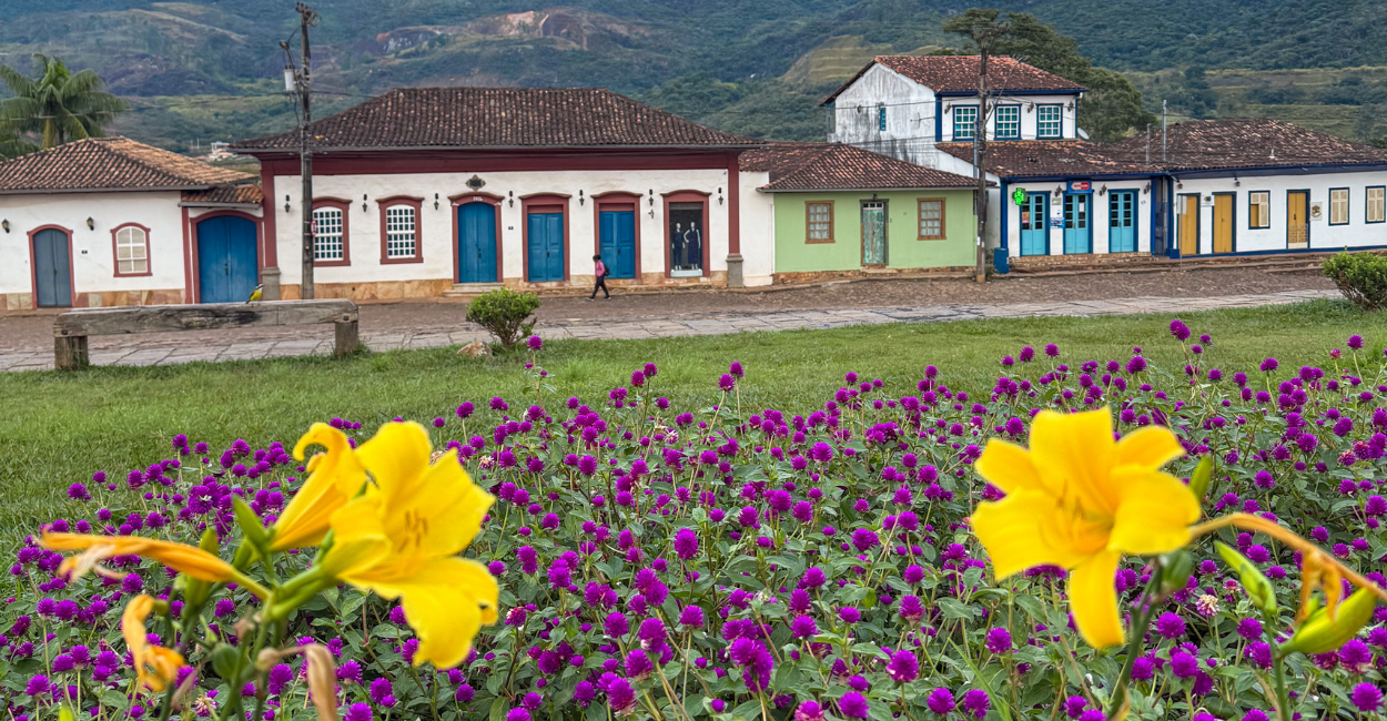 Centro Histórico de Catas Altas, com jardim com flores, montanha e casas históricas, em Minas Gerais