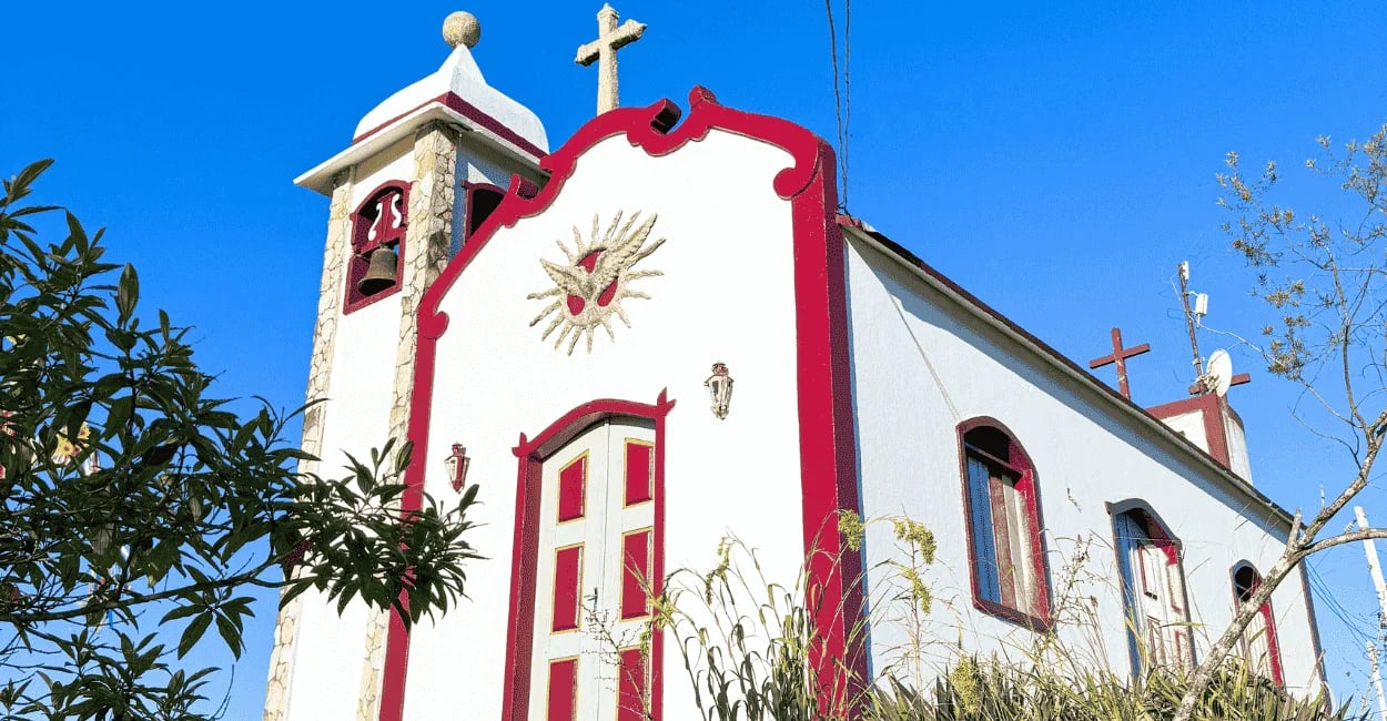 Capela do Senhor do Bonfim com cores brancas e vinho, céu azul sem nuvens em Ipoema