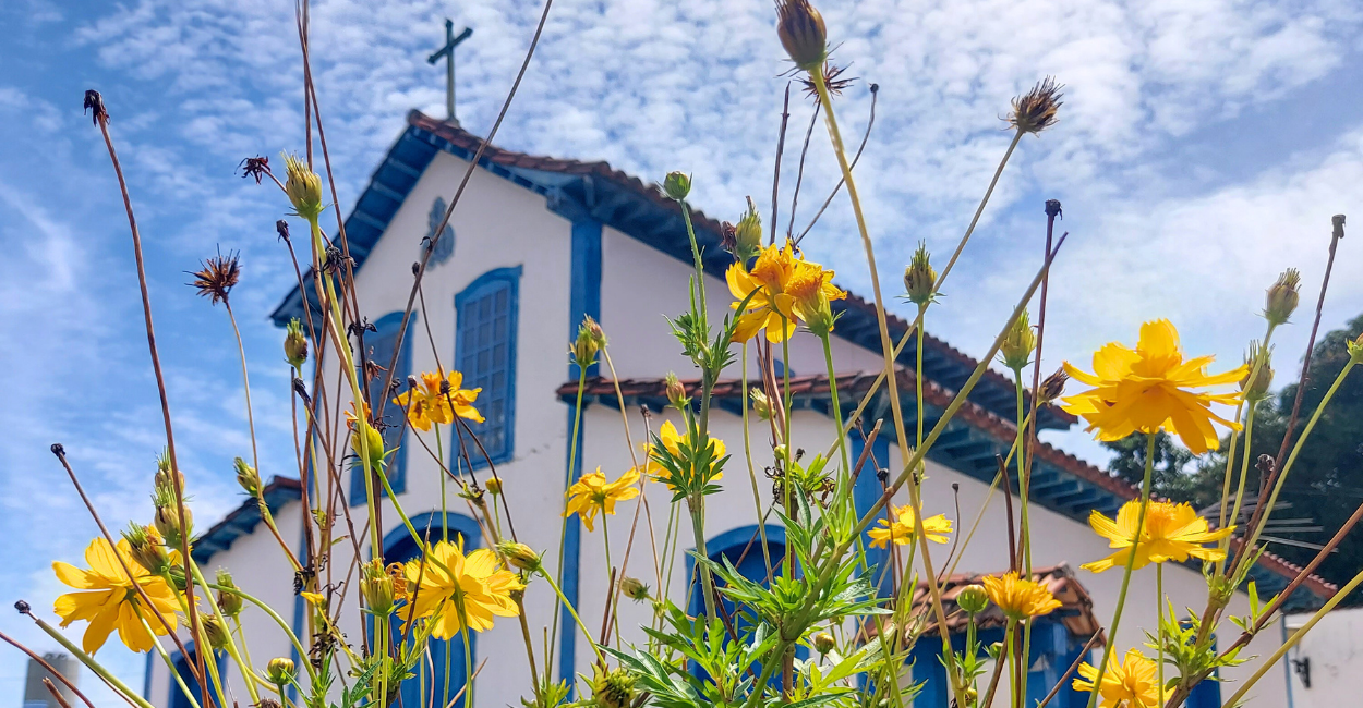 Capela histórica com flores amarelas em frente, em Betim, Minas Gerais, pertinho de BH