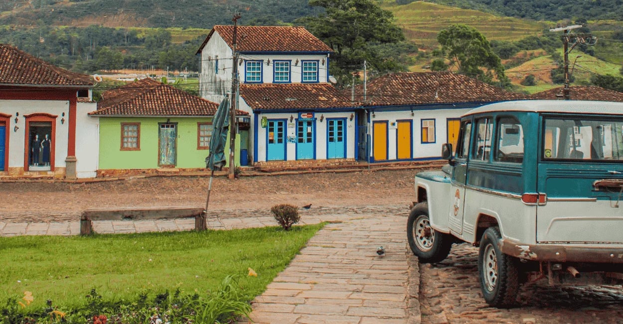 Casario colonial em Catas Altas MG com fachadas coloridas, rua de pedra e veículo antigo