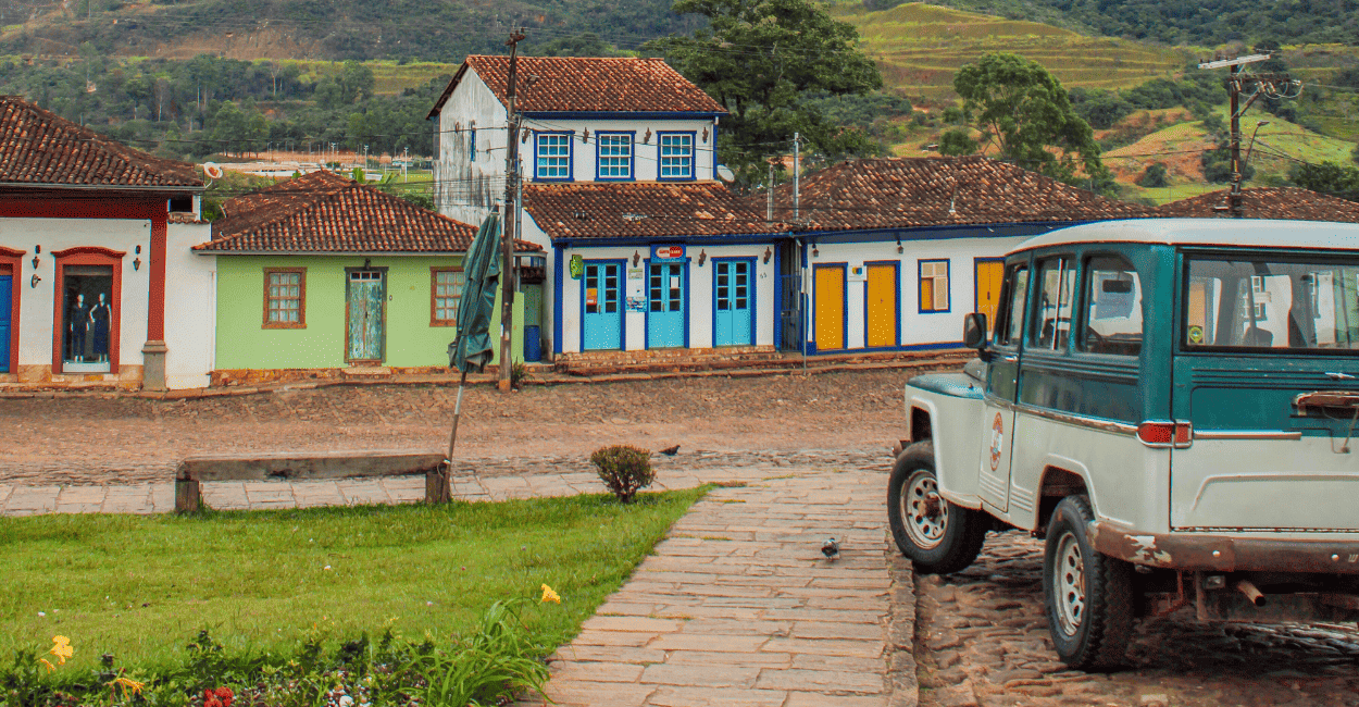 Ruas de pedras com um carro antigo e casas coloniais ao fundo em Catas Altas