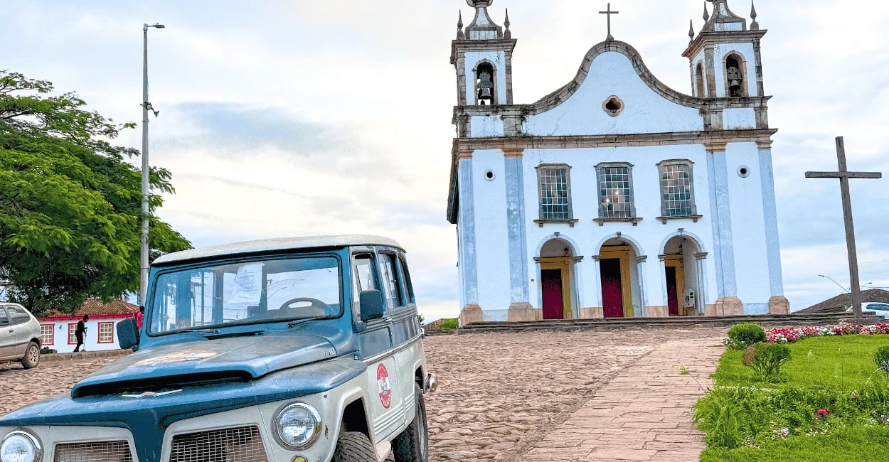 Igreja histórica com carro antigo, rua de pedra e jardim em Catas Altas, Minas Gerais