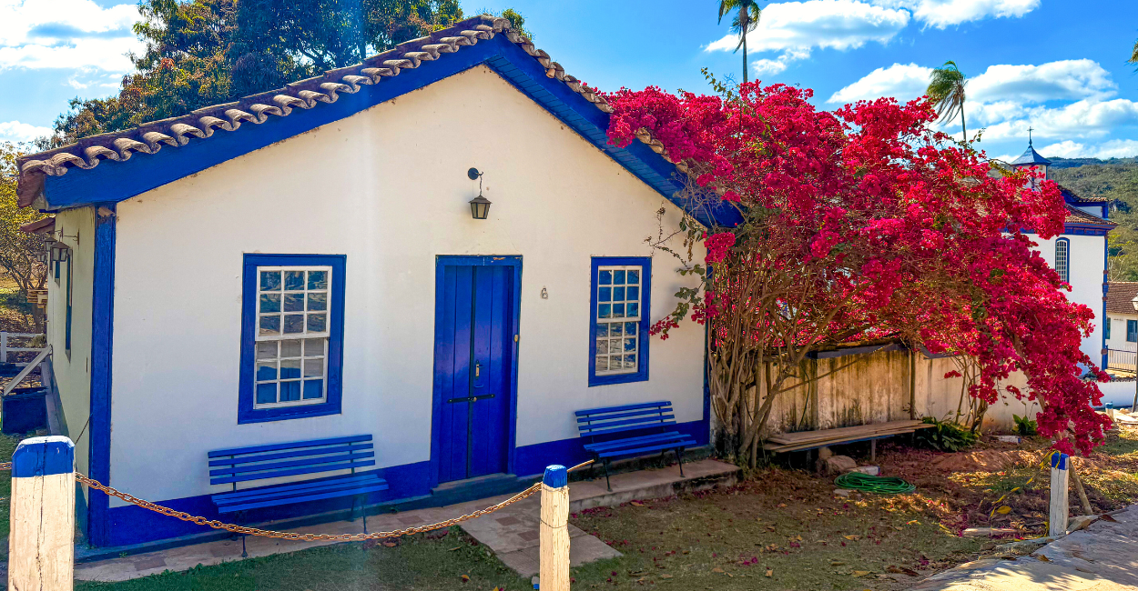 Casa em azul e branco, do periodo colonial, com uma árvore florida em frente, na Vila do Biribiri