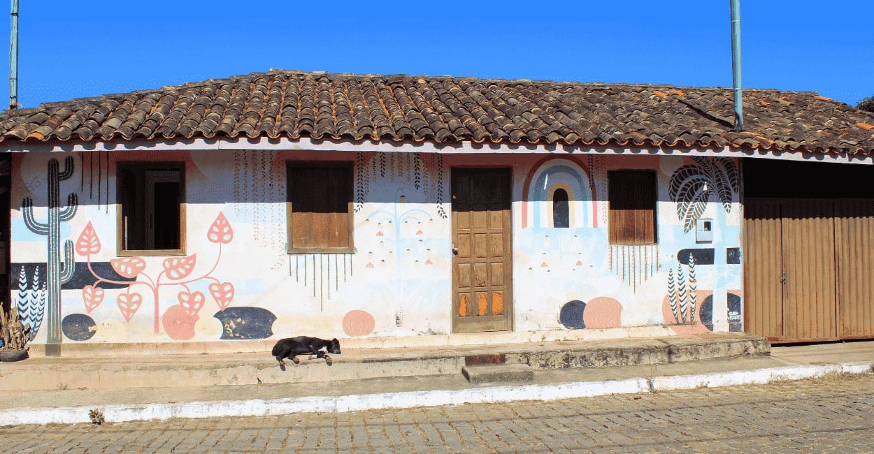 Casa antiga com pintura artística, telhado colonial e rua de pedra em Itatiaia, Minas Gerais