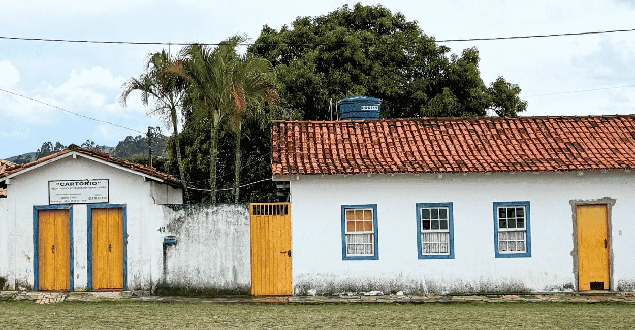 Casa do período colonial com cor branca, janelas azuis e portas amarelas, em Cachoeira do Campo